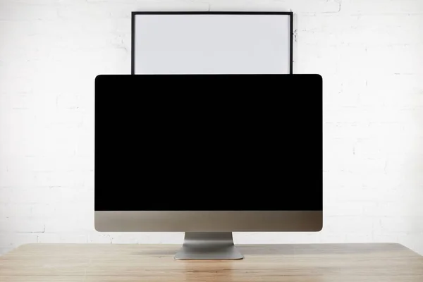 Close up view of designer workplace with blank computer screen on wooden surface and empty white board on brick wall — Stock Photo