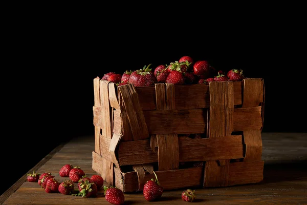 Reife Erdbeeren in rustikaler Schachtel auf Holzoberfläche und auf schwarz — Stockfoto