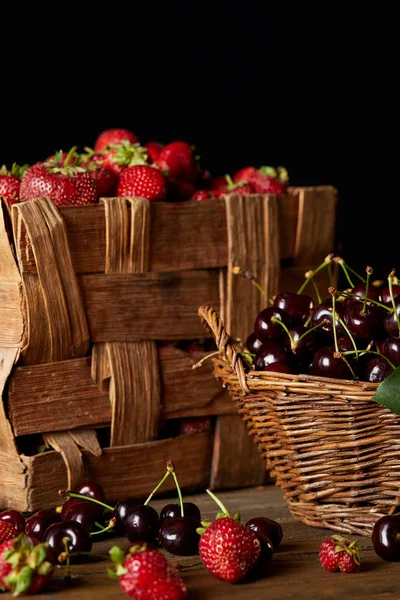 Frische Kirschen und Erdbeeren in Korb und Schachtel isoliert auf schwarz — Stockfoto