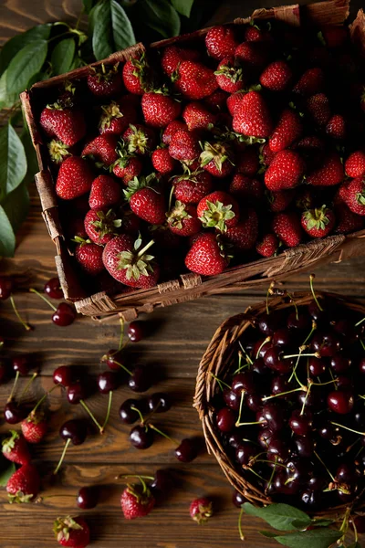 Ansicht von Kirschen und Erdbeeren in Korb und Schachtel auf Holzoberfläche — Stockfoto