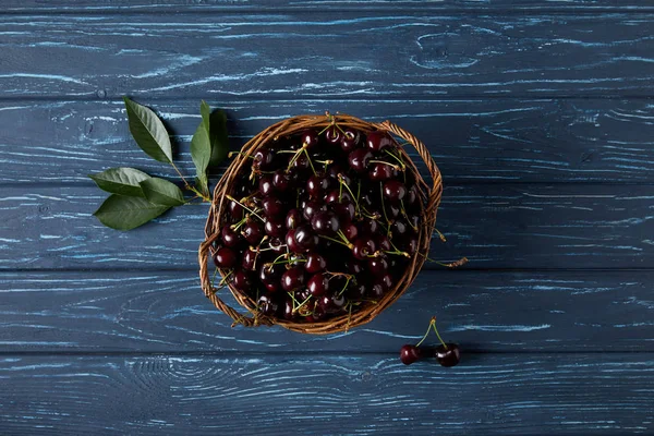 Vue de dessus des cerises douces mûres dans le panier rustique sur la surface en bois bleu — Photo de stock