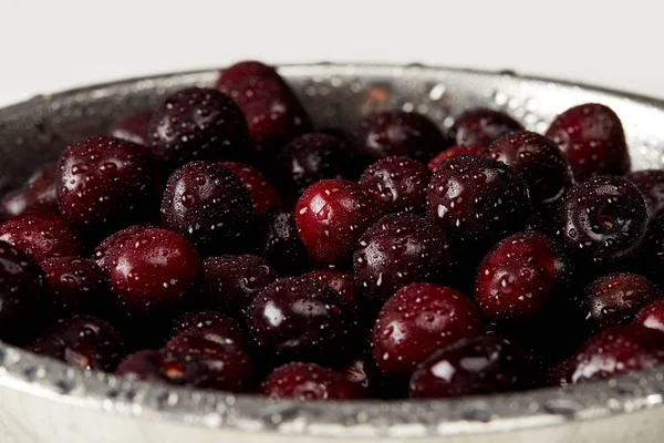 Gros plan de cerises douces fraîches mûres en passoire métallique sur surface blanche — Photo de stock