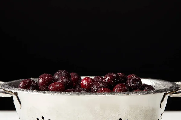 Ripe washed cherries in metal colander on white tabletop — Stock Photo