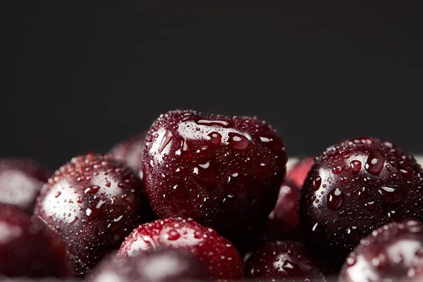 Close-up shot of fresh ripe cherries covered with water drops isolated on black — Stock Photo