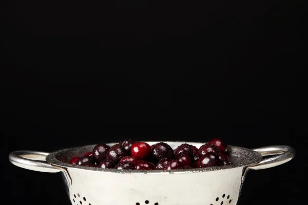 Cerezas frescas maduras en colador aisladas en negro - foto de stock