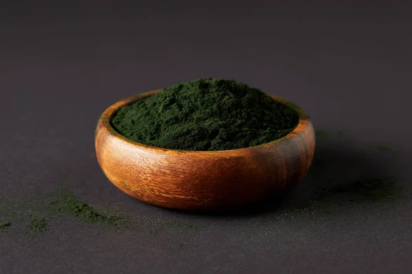 Spirulina algae powder in wooden bowl on grey tabletop — Stock Photo