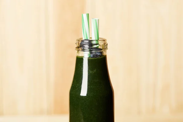 Bottle of spirulina smoothie with blueberries and drinking straw on blurred background — Stock Photo