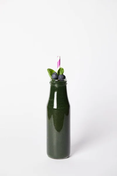 Bottle of spirulina smoothie with mint leaves, blueberries and drinking straw on grey background — Stock Photo