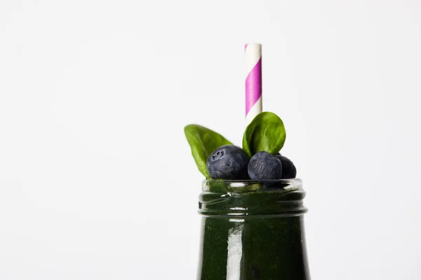 Vista da vicino di bottiglia di Spirulina frullato con foglie di menta, mirtilli e paglia isolata su sfondo bianco — Foto stock