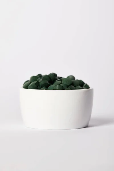 Haufen Spirulina-Pillen in Schale auf grauem Hintergrund — Stockfoto