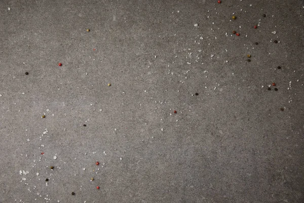 Top view of scattered salt and pepper spices on grey table — Stock Photo
