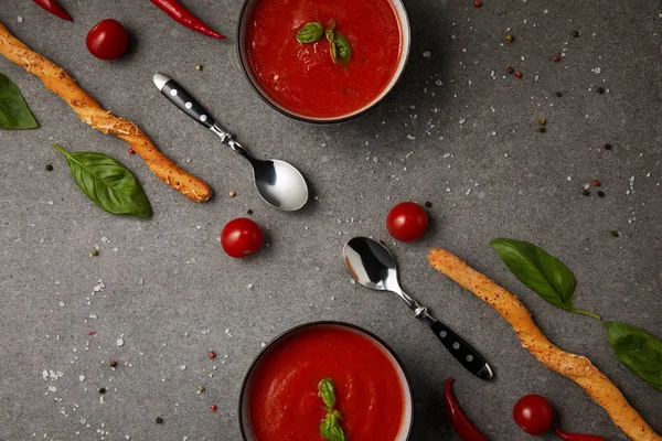 Style alimentaire de soupe aux tomates savoureuse et bâtonnets de pain sur table grise — Photo de stock