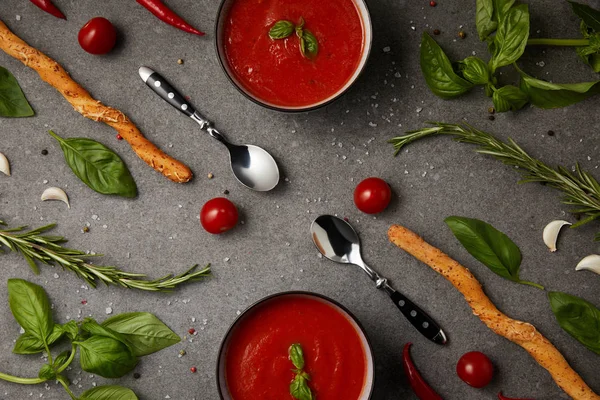 Плоская укладка вкусного томатного супа и хлебных палочек на сером столе — стоковое фото
