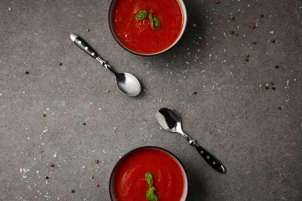 Colocação plana de duas placas com saborosa sopa de tomate e colheres na mesa cinza — Fotografia de Stock