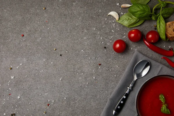 Vue du dessus de l'assiette avec soupe de tomates savoureuse et tomates fraîches sur la surface grise — Photo de stock