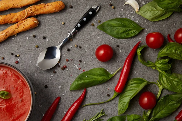 Vue de dessus des légumes savoureux, des bâtonnets de pain et de la soupe aux tomates sur la table grise — Photo de stock