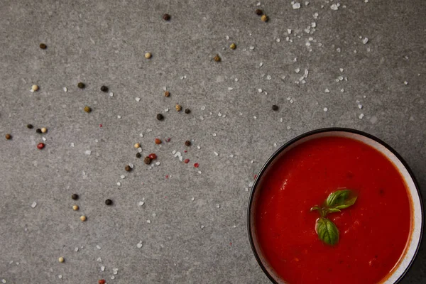 Vue du dessus de la soupe de tomates savoureuse et des épices éparses sur la table grise — Photo de stock