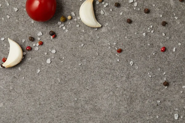 Blick von oben auf verstreuten Pfeffer, Salz, Tomaten und Knoblauch auf grauem Tisch — Stockfoto