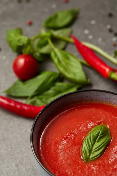 Cooked tomato soup, chili peppers, basil and tomato on tabletop — Stock Photo