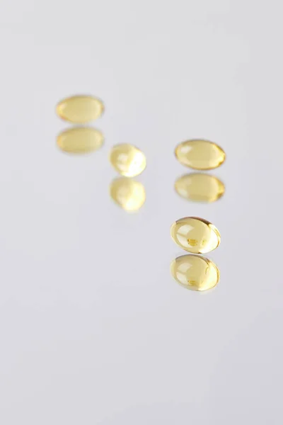 Close-up shot of omega fish hat supplement capsules on reflective surface — Stock Photo