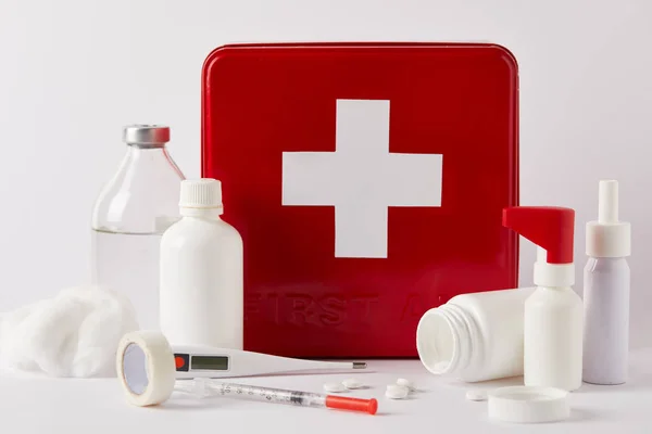 Plan rapproché de la boîte de trousse de premiers soins rouge avec diverses bouteilles médicales et fournitures sur blanc — Photo de stock