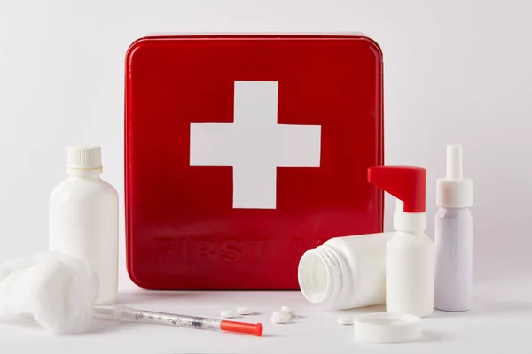 Коробка аптечки с пустыми медицинскими бутылками, шприцем и ватным тампоном на белом — стоковое фото