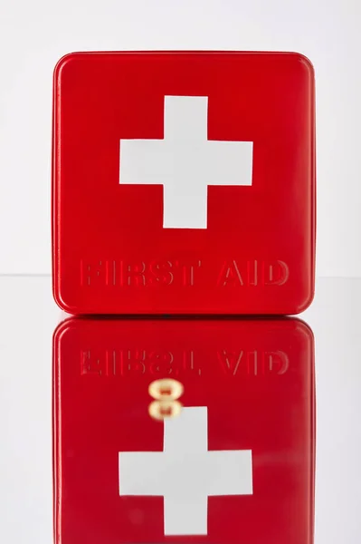 Red first aid kit box with omega capsule on reflective surface — Stock Photo