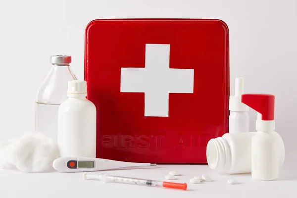Plan rapproché de la boîte de trousse de premiers soins rouge avec différentes bouteilles médicales et fournitures sur blanc — Photo de stock