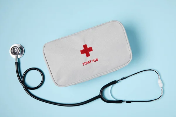 Top view of white first aid kit bag with stethoscope on blue surface — Stock Photo