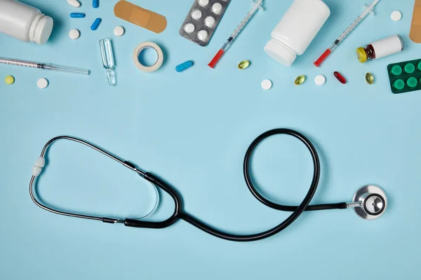 Top view of stethoscope and various medicines on blue surface — Stock Photo