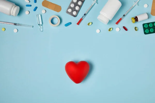 Vista superior del corazón y varios medicamentos en la superficie azul - foto de stock