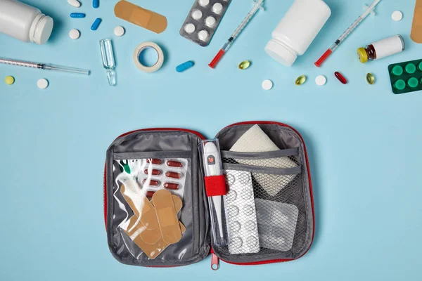 Vue du dessus du sac ouvert de trousse de premiers soins sur le dessus de table bleu — Photo de stock