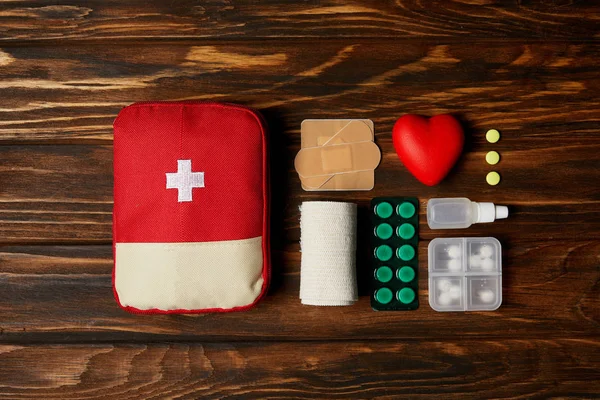 Vista superior de la bolsa del botiquín de primeros auxilios con medicamentos en la mesa de madera - foto de stock