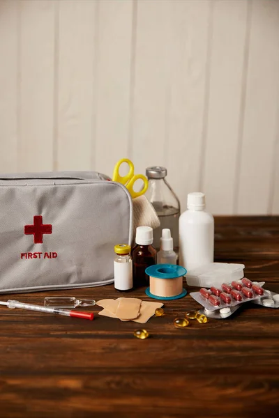 Close-up de kit de primeiros socorros com diferentes medicamentos em mesa de madeira — Fotografia de Stock