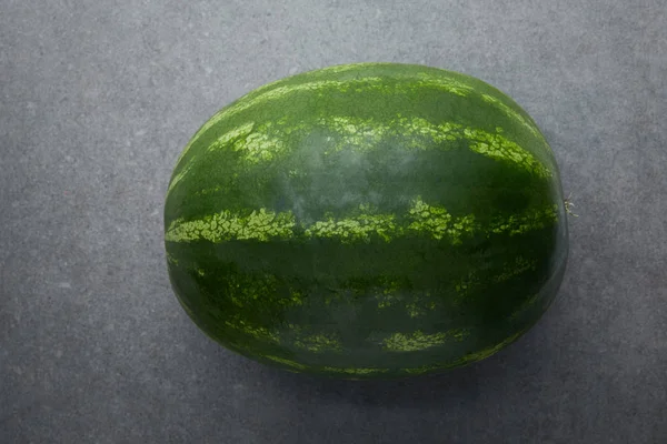 Top view of whole fresh and ripe watermelon on grey concrete tabletop — Stock Photo