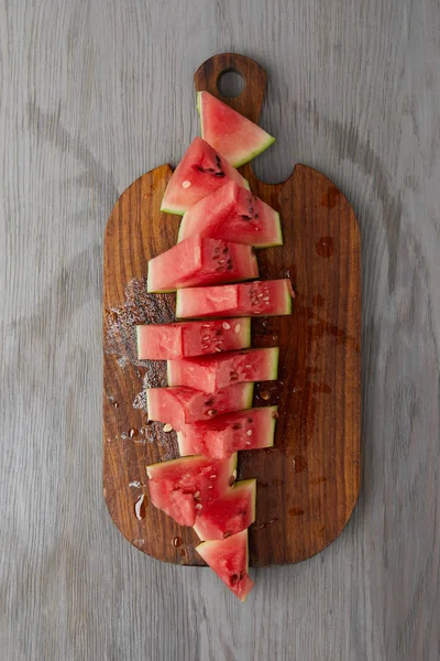 Top view of arranged watermelon slices on wooden cutting board on grey tabletop — Stock Photo