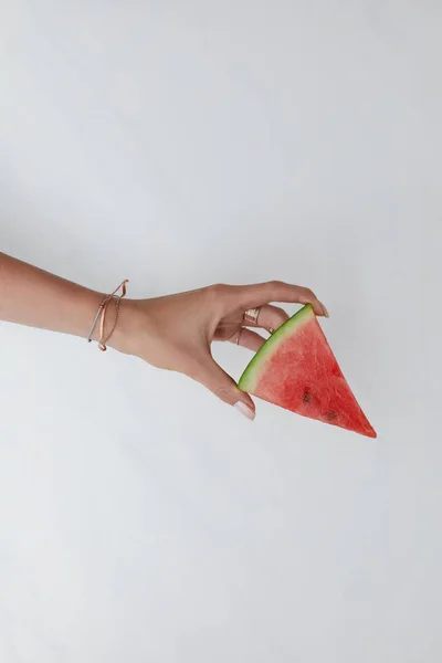Tiro cortado de mulher segurando fatia de melancia na mão em mesa branca — Fotografia de Stock