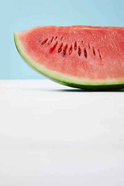 Nahaufnahme der frischen Wassermelonenscheibe auf weißer Oberfläche auf blauem Hintergrund — Stockfoto