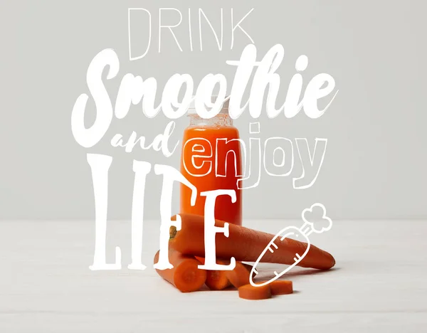 Bottle of detox smoothie with carrots on white wooden surface, drink smoothie and enjoy life inscription — Stock Photo