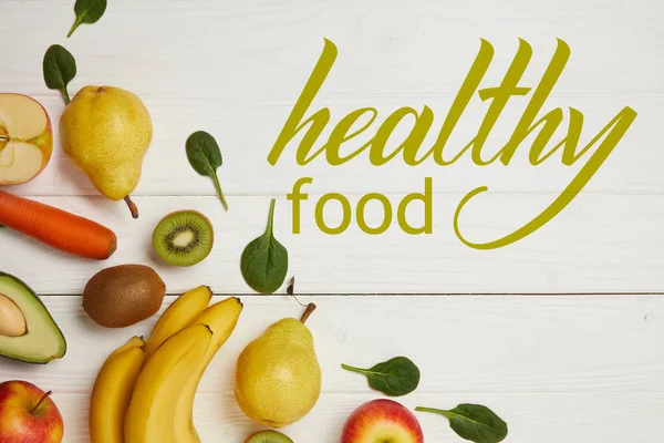 Vue de dessus des fruits frais et des feuilles d'épinards sur fond blanc en bois avec espace de copie, inscription d'aliments sains — Photo de stock