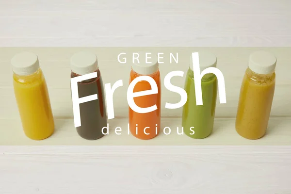 Fresh organic smoothies in bottles standing in row on white, green fresh delicious inscription — Stock Photo
