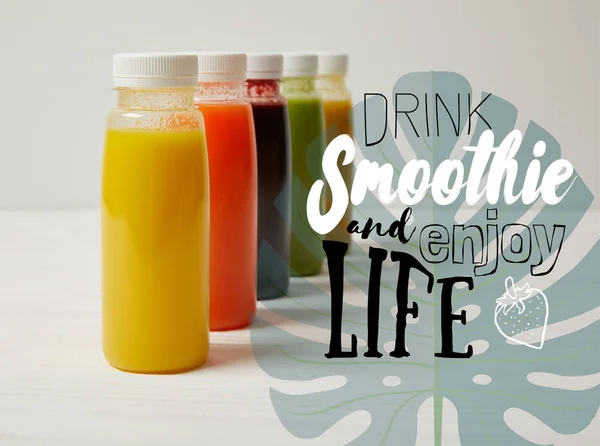 Organic detox smoothies in bottles standing in row, drink smoothie and enjoy life inscription — Stock Photo