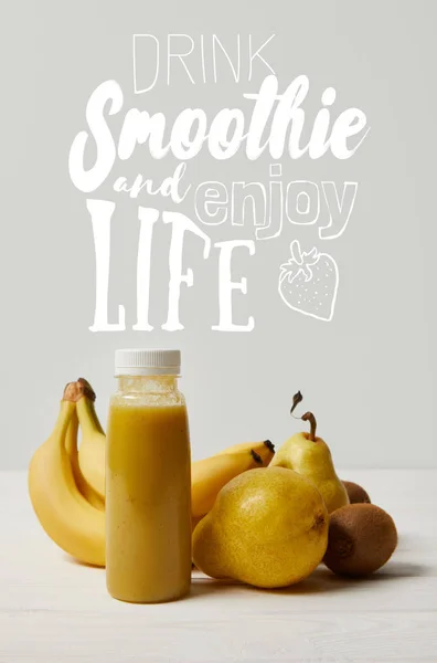 Yellow detox smoothie in bottles with bananas, pears and kiwis on white background, drink smoothie and enjoy life inscription — Stock Photo