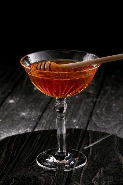 Plan rapproché de verre de miel avec cuillère en bois sur table en bois noir — Photo de stock
