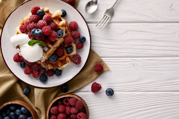 Top view of freshly baked belgian waffles with berries and ice cream on white wooden table — Stock Photo