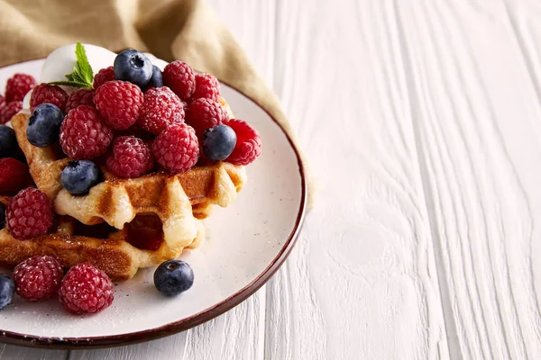 Close-up shot of delicious belgian waffles on plate on white wooden table — Stock Photo