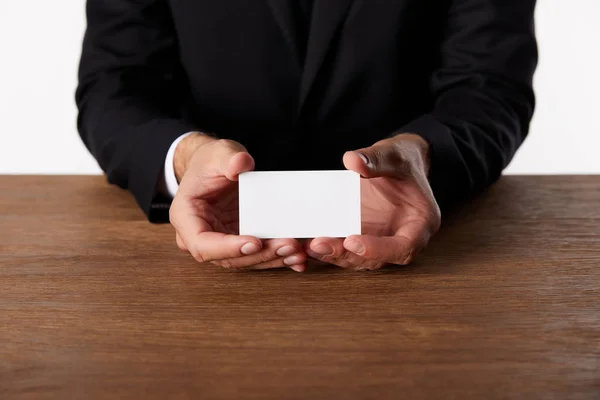 Cropped image of businessman showing empty business card at wooden table — Stock Photo