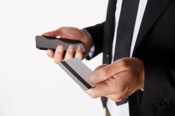 Imagen recortada de hombre de negocios haciendo compras en línea con tarjeta de crédito y smarpthone aislado sobre fondo blanco - foto de stock