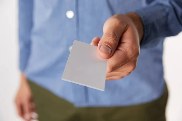 Cropped image of businessman giving empty business card on blurred background — Stock Photo