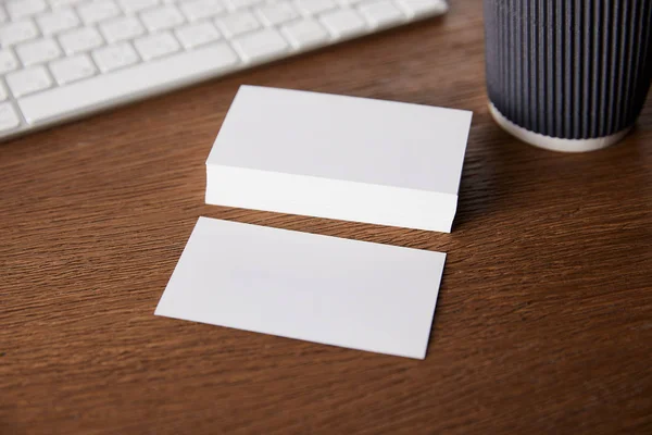 Enfoque selectivo de pila de tarjetas de visita vacías en la mesa con teclado de ordenador - foto de stock